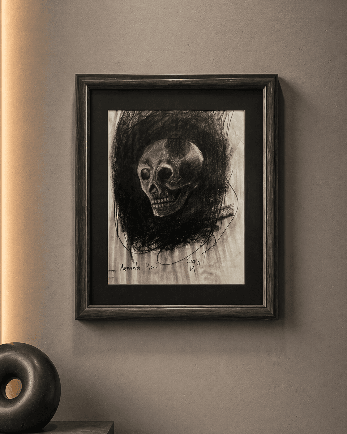 Framed charcoal drawing of a human skull titled Memento Mori on a neutral wall.